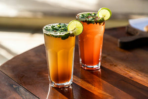 Two colorful drinks garnished with lime and mint