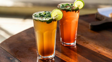 Two colorful drinks garnished with lime and mint
