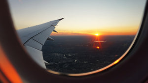 View out a plane window of sunrise and plane wing