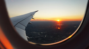 View out a plane window of sunrise and plane wing