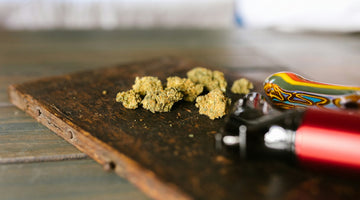 Cannabis buds on wooden surface with pipe