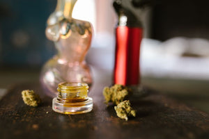 Cannabis concentrate jar with buds and smoking accessories