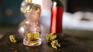 Cannabis concentrate jar with buds and smoking accessories