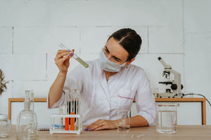 Woman in lab coat testing liquids with test tubes