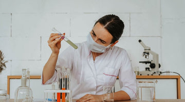 Woman in lab coat testing liquids with test tubes