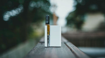 Vape cartridge on a wooden outdoor railing