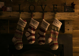 Christmas stockings hanging on rustic fireplace mantel