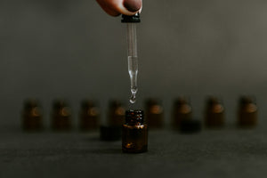 Hand holding dropper above small amber bottle