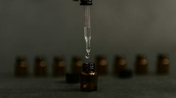 Hand holding dropper above small amber bottle