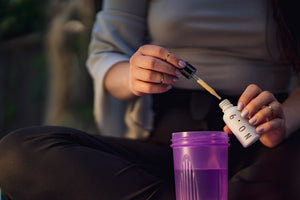 Person adding serum to a purple cup
