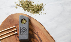 Stone pipe, matches, and herb on wood board