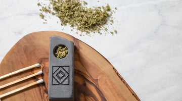 Stone pipe, matches, and herb on wood board