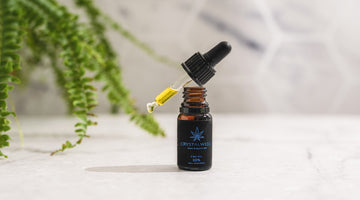 Dropper with yellow oil and bottle on table
