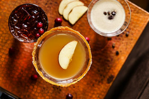 Three cocktails with apple slices and cranberries