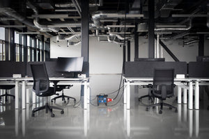 Empty office with desks, chairs, monitors and exposed ducts