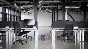Empty office with desks, chairs, monitors and exposed ducts