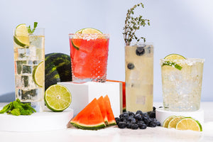 Four colorful cocktails with lime, watermelon, and blueberries